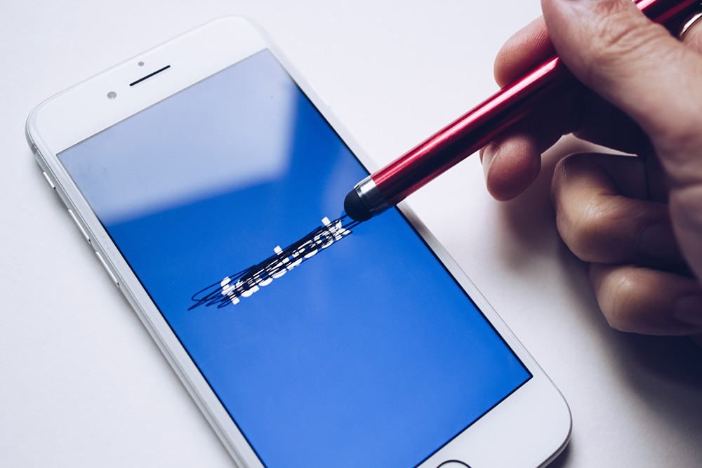 stylus crossing out "facebook" on smartphone screen stylus crossing out "facebook" on smartphone screen